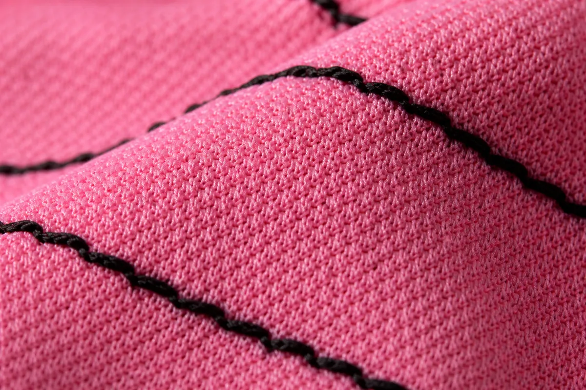 Détail macro d’une maille de polyester rose avec surpiqûres noires